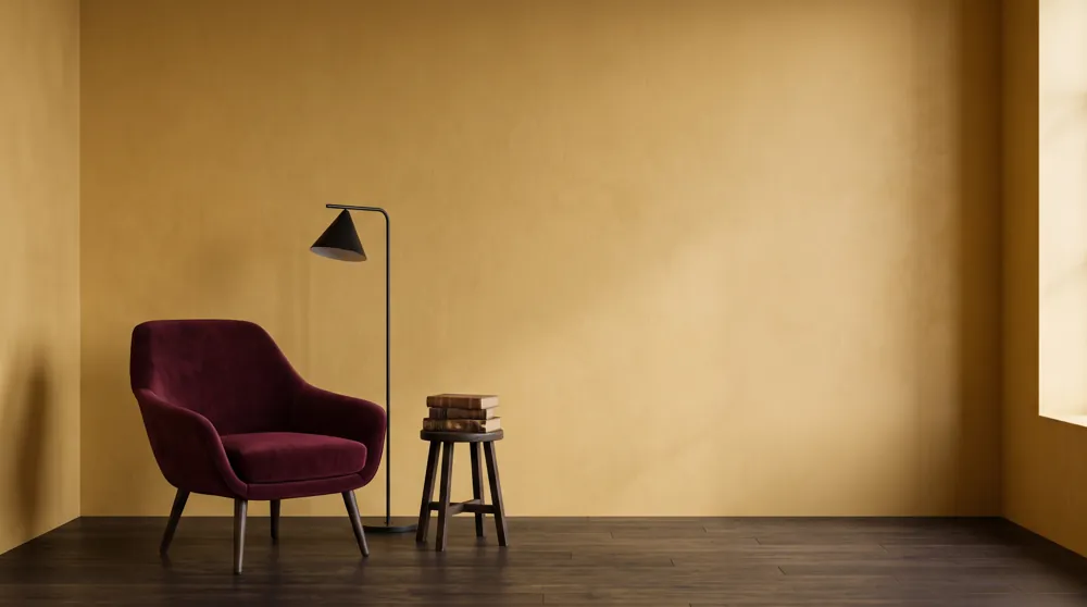 Reading corner with an ochre wall and a burgundy velvet chair